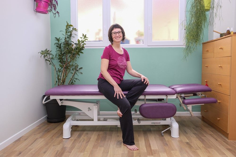 Teku posando sonriente sentada en una camilla de tratamiento para fisioterapia y osteopatía